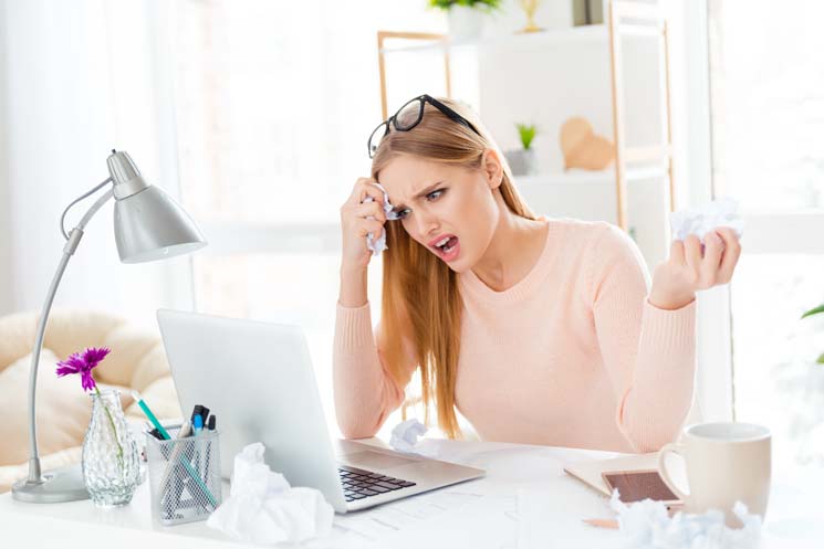 Lady in front of laptop with upset and confused expression